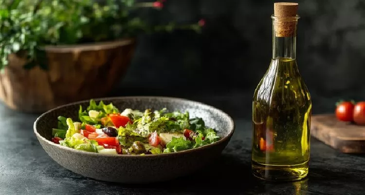 Extra virgin olive oil, a natural source of Vitamin E for healthy, youthful skin, beside a fresh salad.