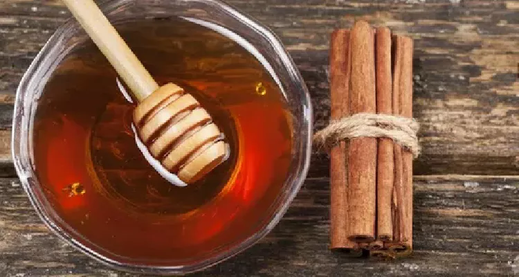 A close-up of honey being drizzled over cinnamon sticks, highlighting the natural combination of honey and cinnamon