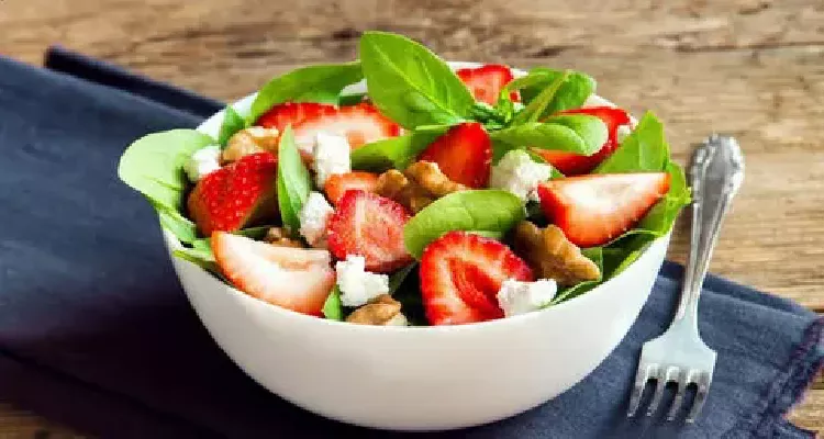 Spinach salad rich in Vitamin E for healthy, youthful skin, featuring strawberries and walnuts