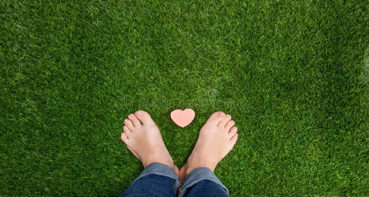 Bare feet on grass forming a heart for earthing and natural health